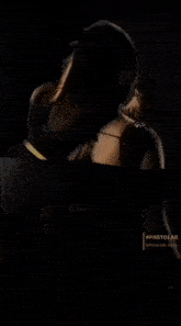 a woman in a black dress is sitting on a black surface