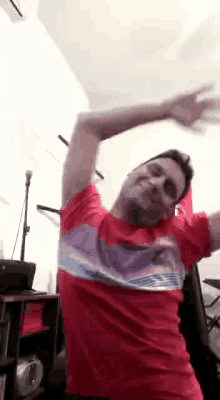 a man in a red t-shirt is dancing in a room .