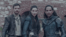 a group of people are standing in front of a brick wall .