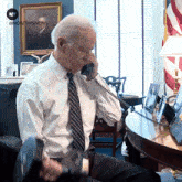 a man in a white shirt and tie is talking on a phone with a now this news logo behind him