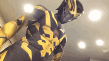 a man in a black and yellow superhero costume stands in front of lights