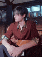 a man wearing a red sweater and a floral shirt is sitting on a couch