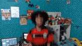 a person in a red shirt is standing in front of a blue wall with posters on it
