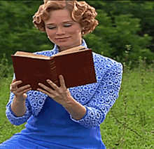 a woman sitting in the grass reading a book