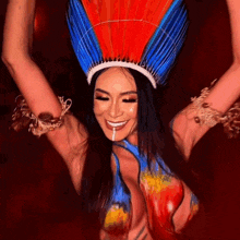 a woman wearing a red blue and white feathered headdress is smiling