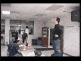 a man in a black shirt is standing in a room with people sitting at tables