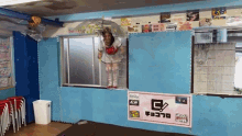 a woman stands in a window with a sign that says g on it