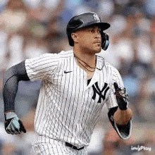 a baseball player wearing a helmet and headphones is running on the field .