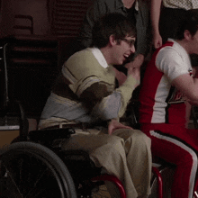 a man in a wheelchair is wearing glasses and a sweater with a striped pattern