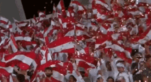 a crowd of people holding up red and white flags