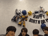 a group of young men are standing in front of a happy birthday sign