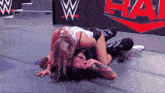 two women are wrestling on a wrestling mat with a w logo in the background