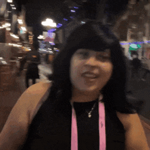 a woman wearing a black shirt and a pink lanyard that says ' a ' on it
