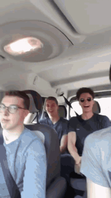 a group of men are sitting in the back seat of a car