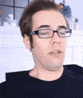 a man wearing glasses and a black shirt is making a face