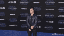 a man in a blue jacket stands on a blue carpet for the star wars movie