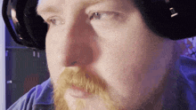 a man with a beard is wearing headphones and looking at the camera