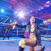 a woman is kneeling down in a wrestling ring with a microphone .