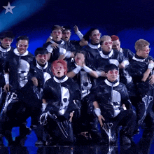 a group of people are dancing on stage with a star in the background