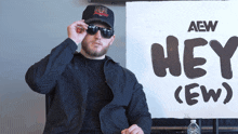 a man stands in front of a sign that says hey ( ew )