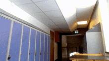 a row of blue lockers in a hallway with a red exit sign above them