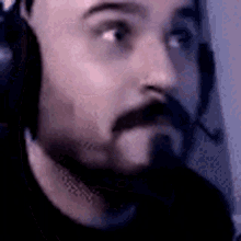 a man with a beard and headphones on is looking at the camera .