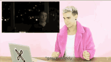 a man in a pink coat is sitting in front of a laptop with a sticker on it that says i love you