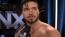 a man with a beard is standing in front of a nxt logo