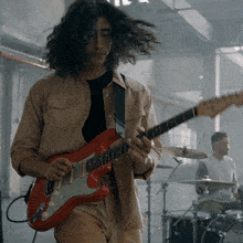 a man is playing a red guitar with the word greischen on it