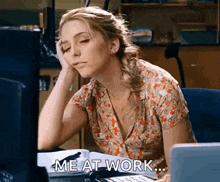 a woman is sitting at a desk in front of a computer with her hand on her forehead .