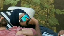a man wearing sunglasses and a turban laying on a couch