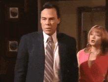 a man in a suit and tie is pointing his finger at someone .