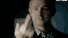 a man is giving the middle finger to the camera in a dark room .