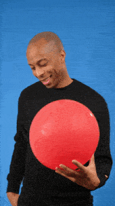 a man wearing a black shirt that says ' a.p.c. ' on it is holding a red balloon