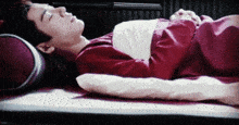 a man in a red shirt is sleeping on a bed