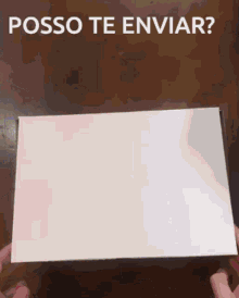 a person holding a white box with the words posso te enviar