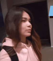 a woman wearing a pink hoodie is looking at something