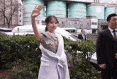 a woman waving her hand in front of a building with a sign that says ' ss ' on it