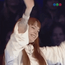 a woman in a white shirt is smiling with her arms in the air