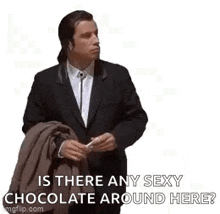 a man in a suit is holding a piece of chocolate and asking is there any sexy chocolate around here .