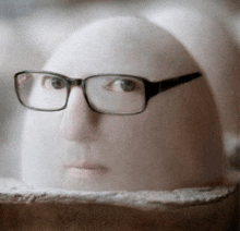 a statue of a man wearing glasses is sitting on a block