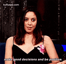 a woman in a black dress is sitting on a couch and talking to someone .