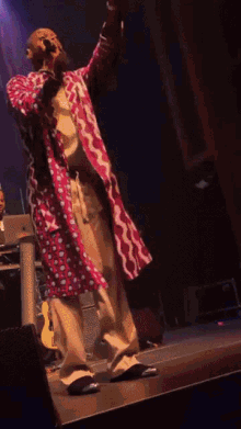 a man in a colorful coat sings into a microphone on a stage