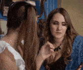 two women are talking to each other and one is wearing a necklace