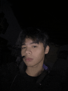 a young man wearing a headset looks at the camera in the dark