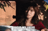a woman is sitting in a car with the words `` i love my life '' written on her face .
