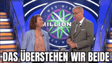 a man and a woman are standing on a stage in front of a million dollar wheel .