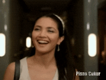 a woman is smiling in a hallway with the words pisau ukur written on the bottom