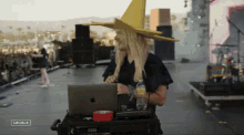 a man wearing a yellow witch hat sits at a laptop