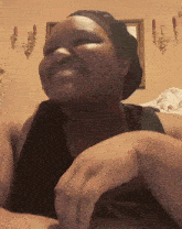 a woman wearing a black tank top and a black hat smiles